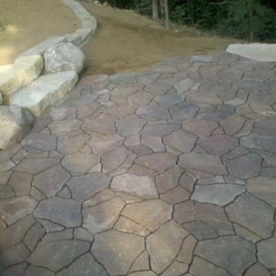 Mega arbel irregular paver patio with stone walls.