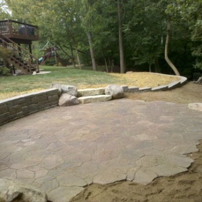 Mega arbel irregular paver patio with stone walls.