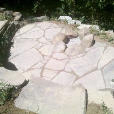 Flagstone patio surrounding granite boulder fire pit