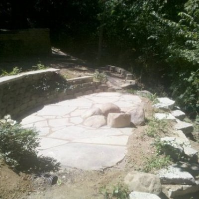 Flagstone patio surrounding granite boulder fire pit